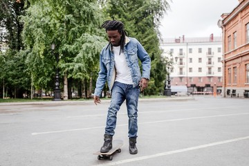African guy learning to ride a skateboard through the streets