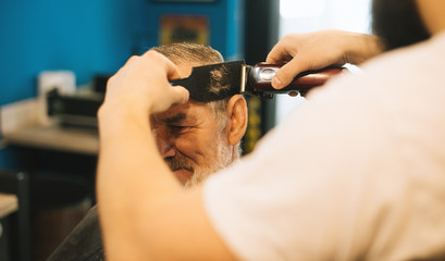 Master cuts hair of men in the barbershop, hairdresser makes hairstyle for a adult man