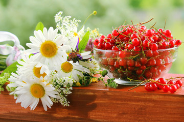 A bouquet of wildflowers and a glass bowl of red currant