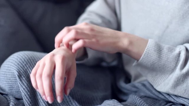 Woman person sitting in modern gray interior chair scratching hands has dry skin problems dermatitis scabies psoriasis rash itch allergy eczema. Unhealthy food stress lifestyle health care concept