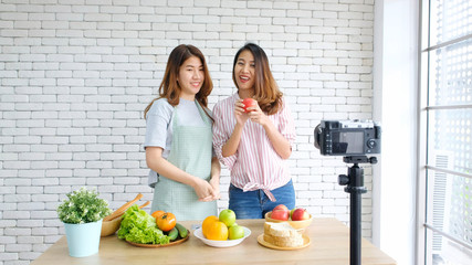 Two young asian women food bloggers talking while recording video with happy moment, vlog concept,...