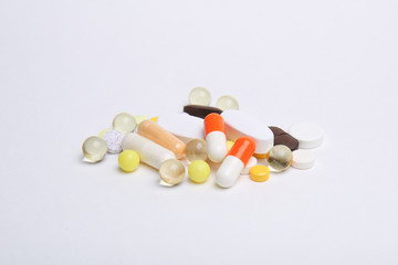A lot of different colored pills in a heap on a white background. Front view.
