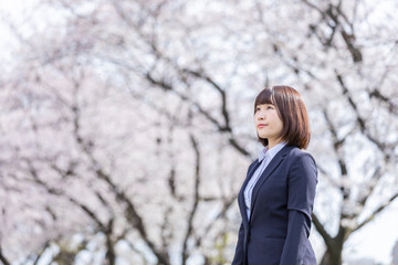 桜とスーツの女性