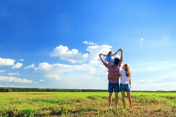 Mom dad and daughter look at the sun in the wheat field. Back view.