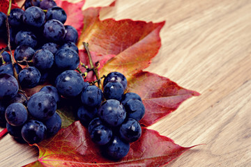 grapes and wine leaves on wooden ground