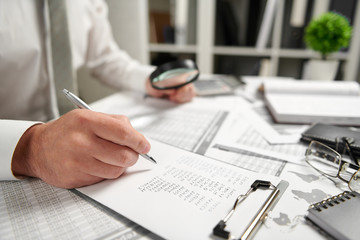 Fototapeta premium Businessman working at office and calculating finance, reads and writes reports. Business financial accounting concept.