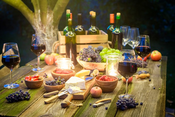 Rustic table with snacks and wine in illuminated garden
