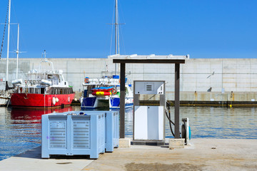 White fuel dispenser at boat filling station on waterfront, port Blanes. Oil industry for water transport. Fishing boats and yachts moored in marina. Seaport Blanes, Spain, Costa Brava, Catalonia