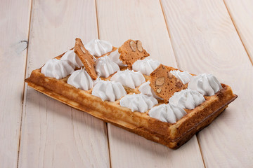 Fototapeta na wymiar Belgian waffle meringue and almond chips. On a light wooden background