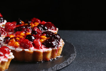 tart with berries on dark background. pie with raspberries and many berries