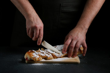chef slices a pie on dark background. pie making concept. recipe of pie or cake