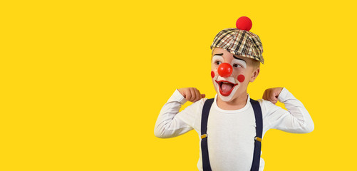 Portrait funny child clown.Cheerful boy,costume,red nose,makeup.Emotional face little comic kid.Happy baby isolated yellow background. concept birthday, holiday, humor. studio,blank,banner,copy space