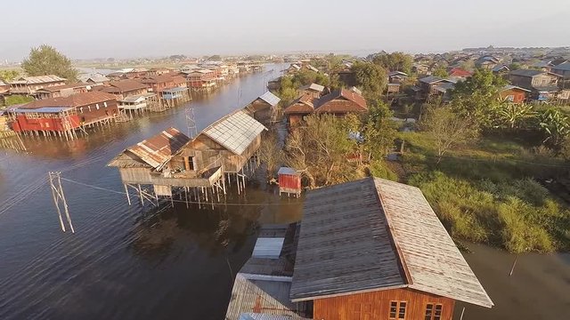 TAUNGGYI, MYANMAR. Aerial shot of peaceful waterscape with tiny wooden houses. Rows of colourful stilt buildings on Inle Lake.