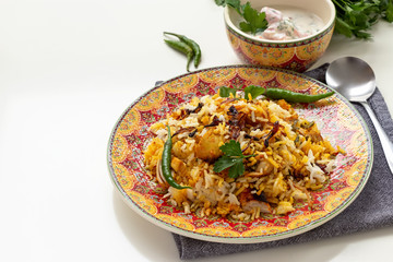 Halal Indian chicken Biryani served with yogurt tomato raita over white background. Selective focus.
