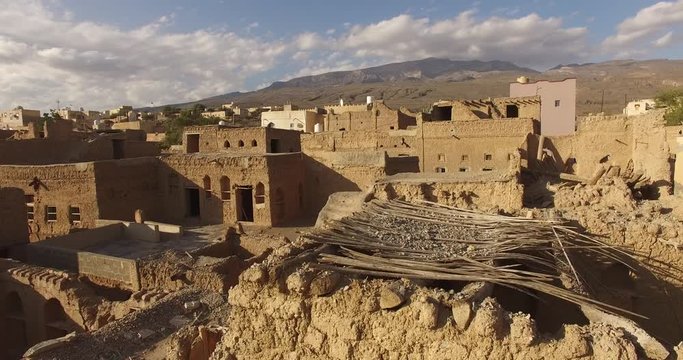 Aerial shot of ancient town surrounded by mountains. Clay and stone houses within desert terrain.