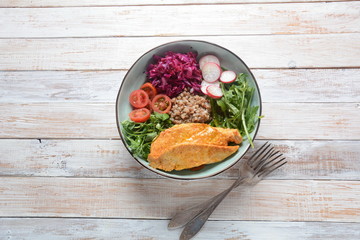 Buddha bowl with red cabbage, tomatoes, radish, arugula beet leaves, pea shoots, buckwheat, grilled chicken. Healthy food concept
