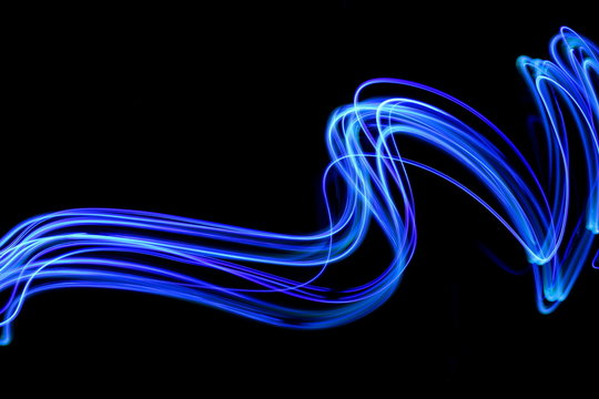 Blue light painting photography, long exposure, blue streaks of vibrant color against a black background