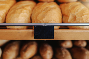Close up of fresh delicious loafs of bread in row on shelves ready for sale. Bakery interior.