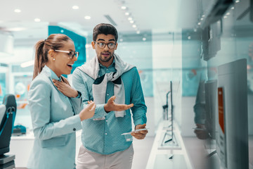 Cute attractive young multicultural couple dressed elegant choosing new plasma television in tech...