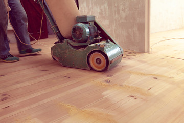 carpenter works by electric grinding wood machine in a room