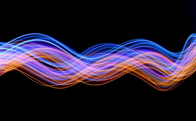 Light painting photography, blue and gold waves and swirls of vibrant color, long exposure photo of fairy lights against a black background