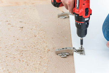 Carpenter install hinges in chipboard white furniture board