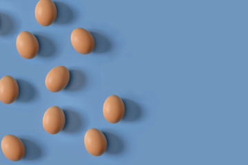 nine brown eggs on a  blue background. The concept of minimalism to your design.