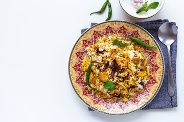 Halal Indian chicken Biryani served with yogurt tomato raita over white background. Selective focus.