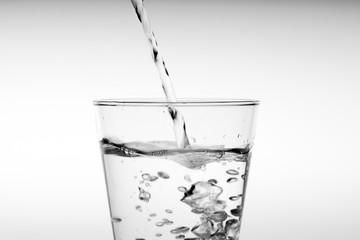 Close up pouring drinking water into glass, studio shot