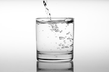 Close up pouring drinking water into glass, studio shot
