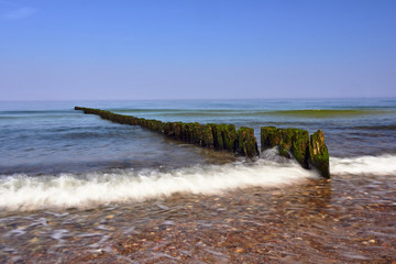 sandy beach and wooden breakwaters on the Baltic coast in  Poland.