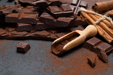 Dark or milk organic chocolate pieces and cocoa powder on dark concrete backgound