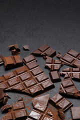 Dark or milk organic chocolate pieces and cocoa powder on dark concrete backgound