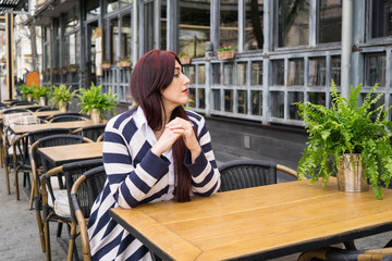 Young lady with long hair sitting alone in cafe