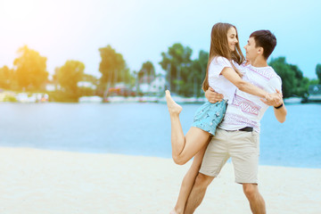 Young couple in love female girl and male man teenagers adults having fun and enjoying weekends near water, river, lake at hot sunny summer day at sand beach. Summer hobbies leisure activities concept