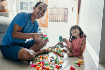 daddy and child playing with plastic brick making some cool design