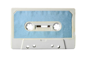 An old vintage cassette tape, obsolete music tech from the 1980s. Dirty ice grey plastic body, cyan blue worn label. Isolated item.