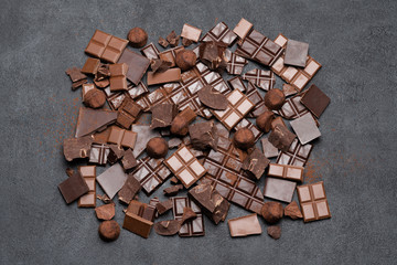 Dark or milk organic chocolate pieces, cocoa powder and truffle candies on dark concrete backgound