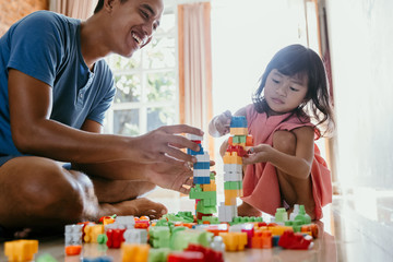daddy and child playing with plastic brick making some cool design