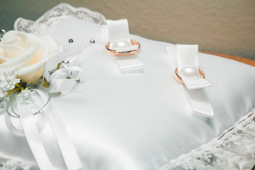 gold wedding rings on a white cushion