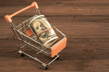 Trolley from the supermarket, American dollar bills on the background of a wooden table. business, Finance, money.