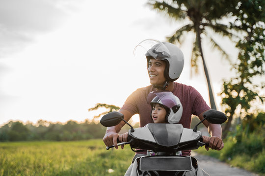 Fahter And His Child Enjoy Riding Motorcycle Scooter In The Countryside Road