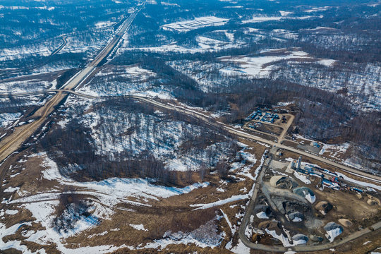 Helicopter drone shot. Aerial photography of a modern roads with car, track in winter, on background forest, construction site, no people