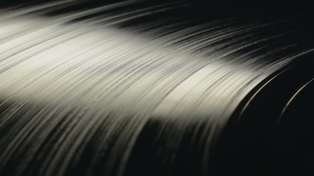 Modern vinyl record plate rotating in beautiful soft light, view from top, close up