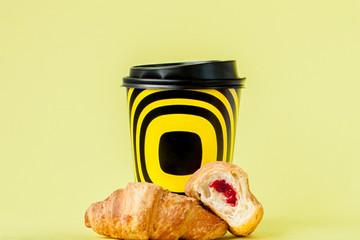 Paper cup of coffee and croissants on a yellow background, Copy space