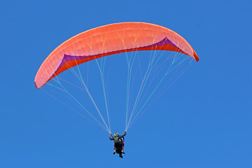 Tandem paraglider flying red wing