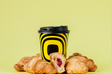 Paper cup of coffee and croissants on a yellow background, Copy space