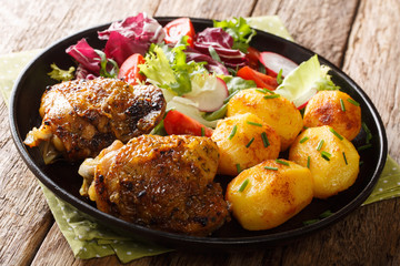 full dinner of chicken thighs with new potatoes and fresh salad close-up on a plate. horizontal