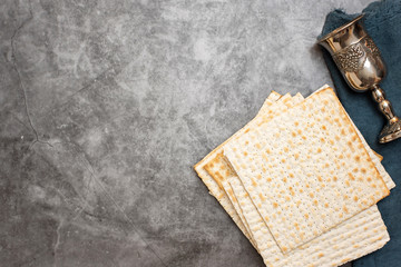 Jewish Passover holiday. Matza and glass for wine on a grey background. Top view. With copy space