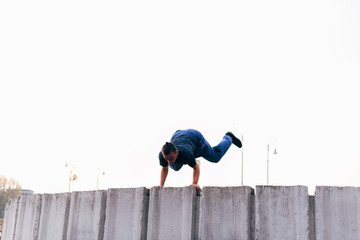 Caucasian man trains parkour while jumping over a high top.